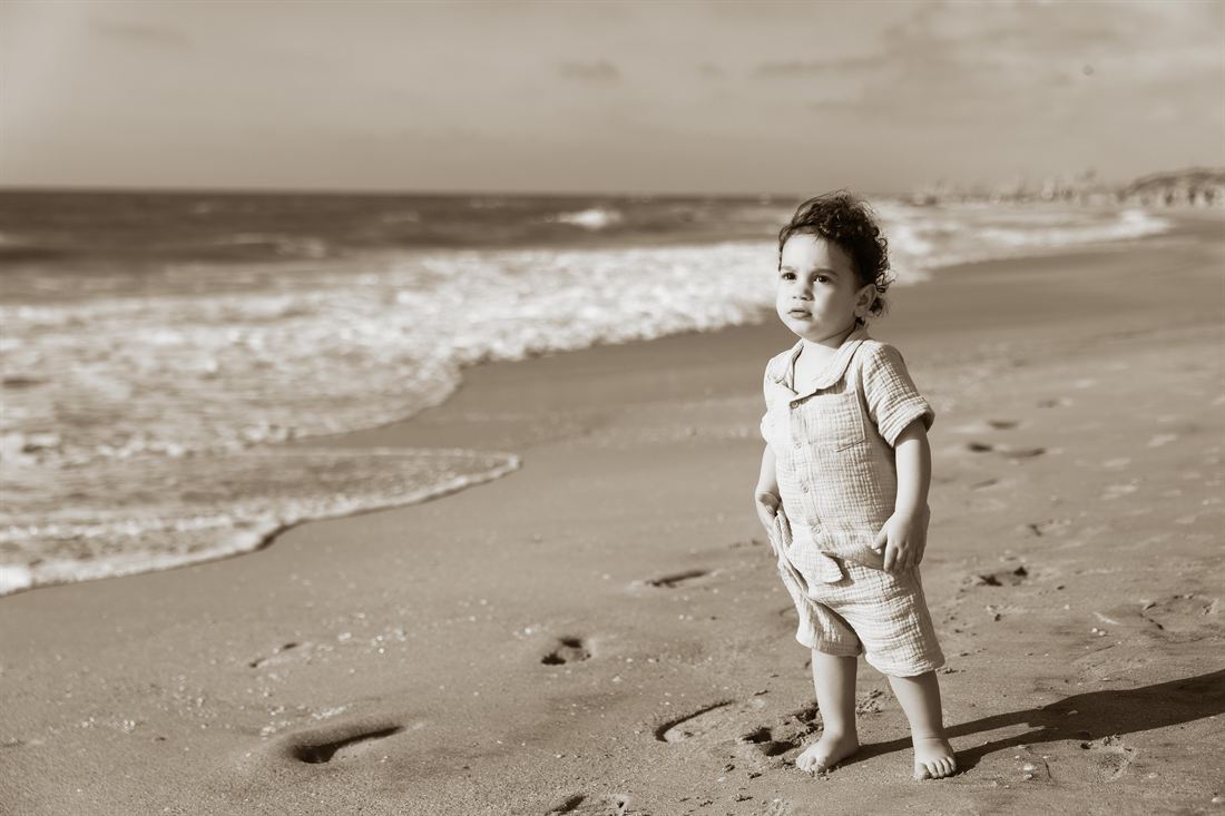 Sepia-toned portrait of a child standing on the beach.