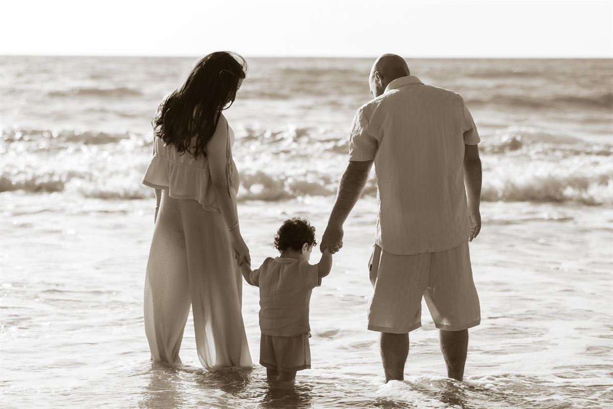 Family holding hands while standing together in the sea.